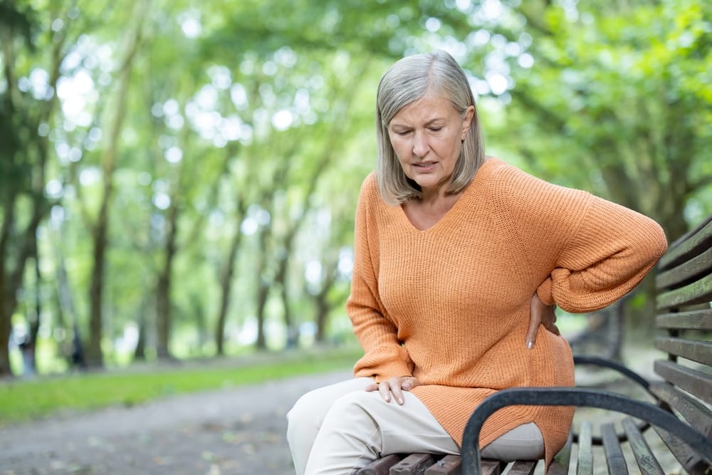 woman on park bench suffering from hernia